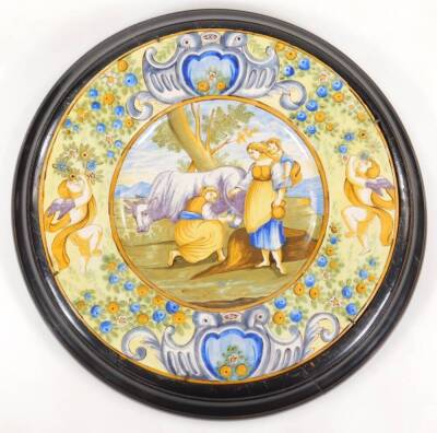 A pair of Italian Maiolica wall plaques, each of circular form, the first centred with figures and cattle, the second a classical scene with further figures with scroll borders broken by flowers and cherubs, predominately in green, orange and blue, unmar - 2