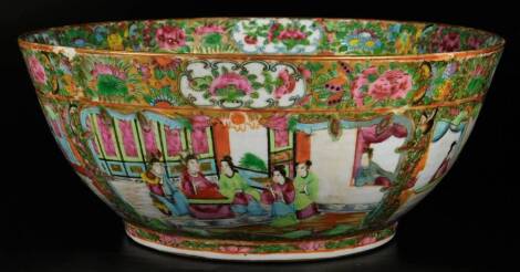 A Cantonese porcelain punch bowl, of circular form, profusely decorated with figures in an interior setting, broken by further panels of flowers, predominately in pink, green and yellow, unmarked, 30cm Dia.