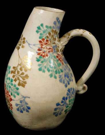 A 19thC Kenzan satsuma Tokonoma Japanese jug, with shaped spout, scroll handle and bulbous body, polychrome decorated with flowers predominantly in blue, green and red, with gilt highlights, 14cm H.