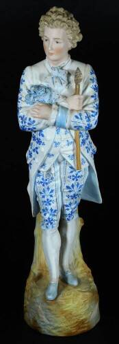 A continental bisque porcelain figure of a gentleman, standing holding lorgnette, in floral finery, predominately in blue, on a naturalistic base, unmarked, 44cm H.