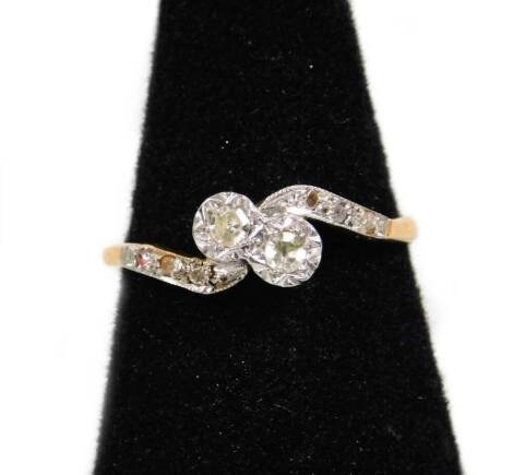 An 18ct gold and platinum diamond twist ring, with two central diamonds and diamond set twist shoulders, ring size O, 2.1g all in.