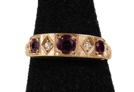 A 9ct gold dress ring, with three large garnets and two tiny diamonds forming a five stone design central panel, with floral shoulders, ring size O, 3.5g all in.