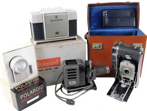 Various optical equipment, etc, comprising, a Leitz Prado 150 slide projector, 16cm H, (boxed, with accessories), a Polaroid model 150 land camera, in brown leather case with further accessories, Wink Light model 252, and a Polaroid print copier 240. (a q