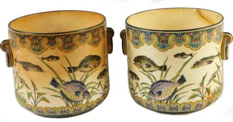 A pair of early 20thC pottery jardinieres, each of cylindrical form with moulded handles, polychrome decorated with fish, with an upper geometric banding on a circular foot no. GP287 probably continental,19cm H. (2)