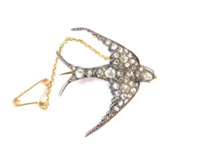 A Victorian swallow brooch set with old cut diamonds, with ruby glass eyes, set in white and yellow metal with safety chain as fitted, 7.4g.