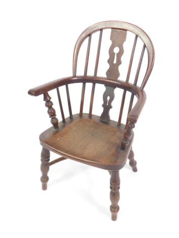 A 19thC child's oak and elm Windsor chair, with a keyhole splat and spindle back, solid saddle seat, raised on baluster and ring turned legs, united by a crinoline stretcher.