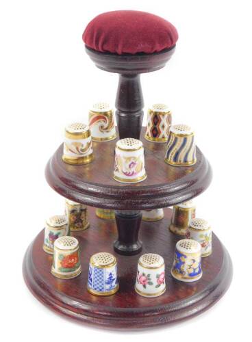 A Royal Crown Derby Historical Thimble Collection, comprising fifteen thimbles with booklets on a two tier wooden stand.