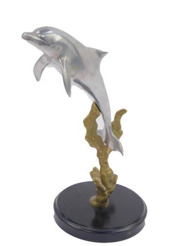 An aluminium and brass model of a dolphin, riding above seaweed, raised on a circular base, 25cm H.