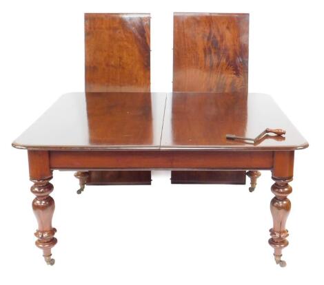 A Victorian mahogany wind-out dining table, with two additional leaves, raised on turned and lappet carved legs, brass capped on castors, with winder, 74cm H, 150cm W, 250cm W with leaves, 132cm D.