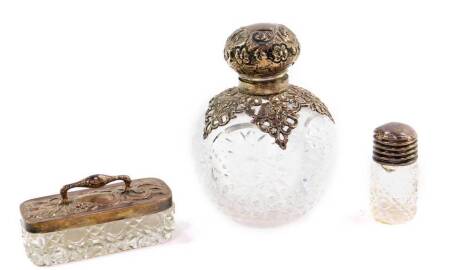 An Edward VII cut glass and silver mounted scent bottle, embossed with roses and rococo scrolls, Birmingham 1902, 11cm H, together with a cut glass pin dish, with silver lid, Birmingham 1903, and a cut glass smelling salts jar with silver screw lid, Birm