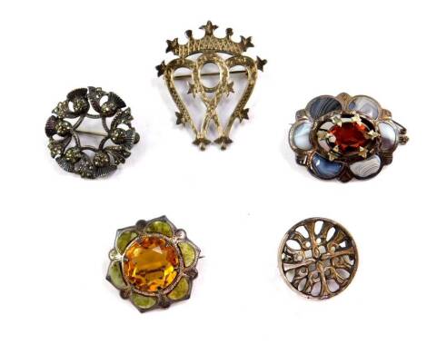 Five Scottish silver brooches, one set with a Cairngorm and agates, another similar of oval form, double heart brooch with coronet surmount, circular marcasite set thistle brooch, and a circular Celtic brooch.