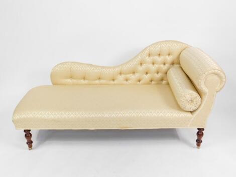 A Victorian style mahogany chaise longue, upholstered in button back gold brocade fabric raised on turned legs, on brass castors, 162cm W, 62cm D.