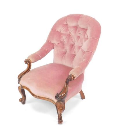 A Victorian walnut nursing chair, with pink buttoned back upholstery and overstuffed serpentine seat, raised on cabriole legs.