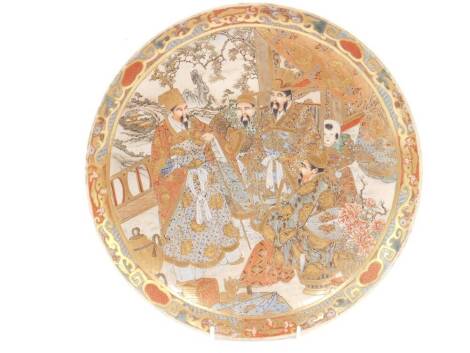 A Japanese Meiji period Satsuma dish, decorated with figures in an interior, with landscape beyond, 30cm Dia.