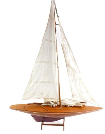 A model of a yacht, with a wooden hull, fully rigged with sails, on a stand, 92cm L.