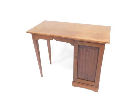 A Victorian oak kneehole desk, with a single pedestal, having two linen fold doors, opening to reveal four trays, raised on bracket feet, and tapering square legs, 72.5cm H, 91cm W, 46cm D.