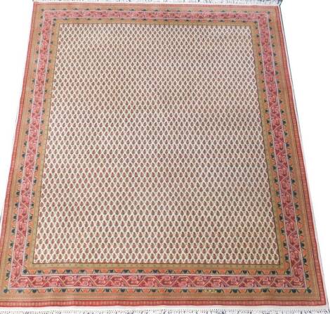 A Persian rug, decorated with repeating botehs against a cream ground, within floral banded borders, 261cm x 204cm.