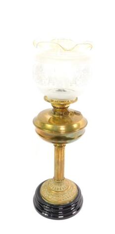 A Duplex brass oil lamp, with a fluted column and embossed foliate base, raised on a black pottery socle, with chimney and etched clear glass shade, with an amber rim, 70cm H.