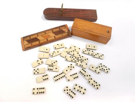 A set of bone and ebony dominoes, oak cased, together with two wooden cribbage boards, one with brass pegs. (3)