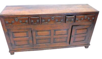 An 18thC oak dresser base, the rectangular planked top with a moulded edge above an arrangement of three long, two short drawers and four panelled doors on stiles, 81cm H, 151cm W, 43cm D.