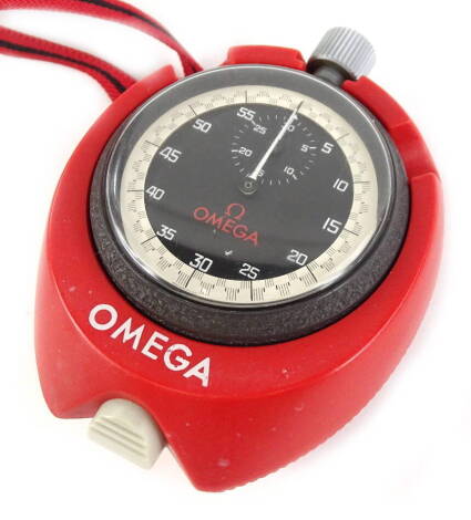 An Omega stop watch, with black dial and white seconds border, in red plastic casing with lanyard.