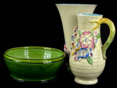 A Clarice Cliff relief moulded floral ewer or jug, with ribbed body, tapering vase, a similar vase of tapering form and a Bretby green glazed bowl. (3)