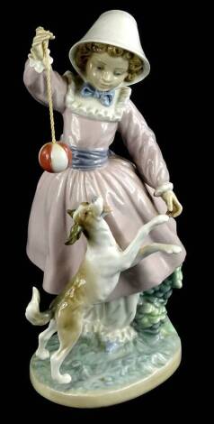 A Lladro porcelain figure group, modelled in the form of a young girl teasing a dog with a ball toy, 27cm H.