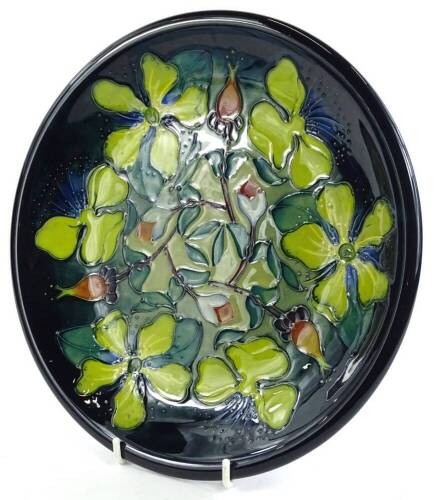 A Moorcroft pottery plaque or charger, decorated with yellow and orange flowers, on a mottled blue and green ground, impressed and hand painted marks to underside, 26cm dia.
