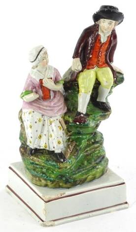 A 19thC Staffordshire pottery figure group, modelled in the form of a gentleman seated on a rock beside a lady, on square base, numbered 36 (AF), 22cm H.