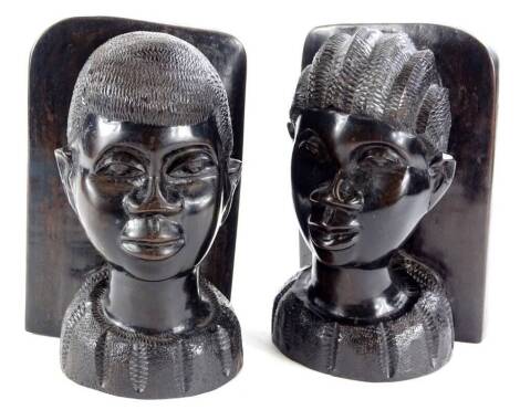 A pair of African tribal bookends, each carved with a male and female bust, 23cm H.