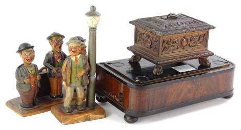 A late 19thC mahogany and ebonised music box case, with bun feet, previously with a glass dome etc., a continental music box in a carved case, and a Black Forest or Swiss type bottle opener stand and similar drink stand, each piece carved with gentleman e