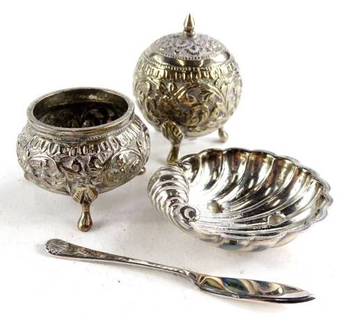 A collection of silver and white metal, to include a circular salt embossed with scrolls etc., a similar salt, a shell shaped salt and a small butter type knife. (4)