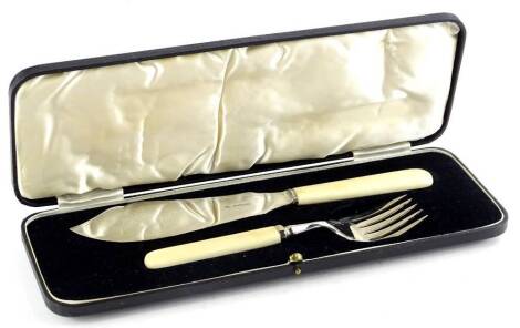 A George V silver fish serving set, comprising knife and fork, each with a composition handle in a fitted case, Sheffield 1935.