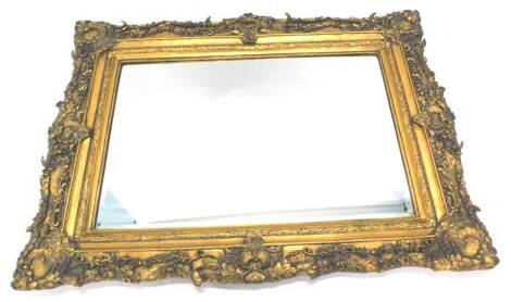 A gilt rectangular wall mirror, with a bevelled plate and a frame decorated with swags, scrolls etc. 93cm x 143cm.
