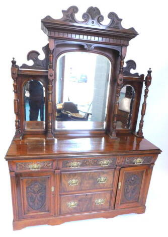 A late Victorian walnut and figured walnut sideboard, the raised back with a shaped crest above three arched bevelled mirror plates, on turned supports, the base with three frieze drawers above two further drawers, flanked by two panel doors on bracket fe