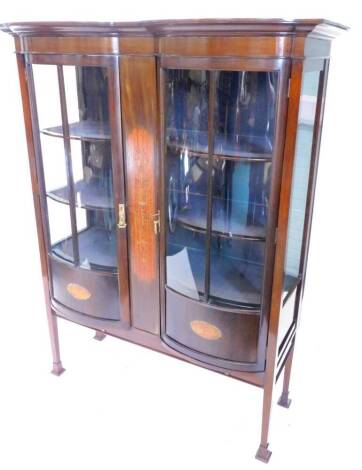 An Edwardian mahogany display cabinet, the moulded cornice above two glazed bow fronted doors, flanking a central satinwood and marquetry panel of an urn, flowers, swags etc., on square tapering legs with spade feet, 141cm W.