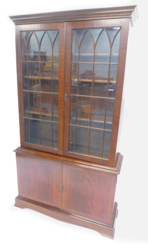 A mahogany bookcase in George III style, the top with two glazed doors, the base with a slide and two panel doors on ogee bracket feet, 101cm W.