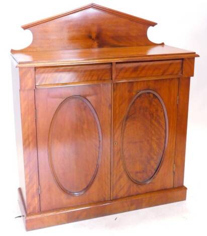 A Victorian mahogany and satin birch side cabinet, with a raised back above a moulded top and two frieze drawers above a pair of doors with oval panel on a plinth, 96cm H, 104cm W. Provenance: The property of Joan Stephenson, Kirkwood, North Church Walk, 