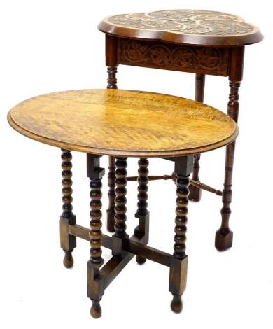 An early 20thC carved oak occasional table, the trefoil shaped top decorated with flowers, leaves etc., surrounding a swan and signet crest above a leaf carved frieze on turned tapering legs with X shaped stretcher, 52cm W, and an oak oval folding table o