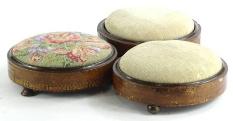 Three Victorian walnut foot stools, to include an example with a padded woolwork seat and a parquetry band, each on bun feet.