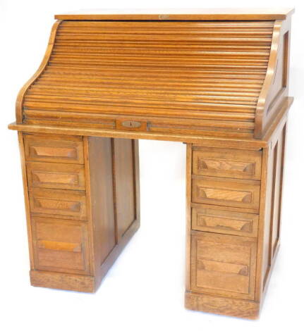 An early 20thC oak roll top desk, the tambour front enclosing a fitted interior above four drawers to each pedestal on plinth, 107cm W.