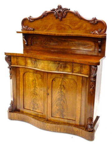 A Victorian mahogany chiffonier, the raised back carved with scrolls and with a shaped shelf, the base with a frieze drawer and above two doors with arched panels, flanked by carved bosses, on a plinth base, 144cm H, 122cm W, 48cm D.