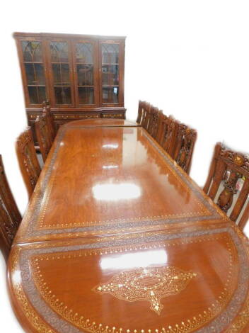 An Eastern hardwood brass and copper inlaid extending dining table, comprising two D shaped ends, the central rectangular section with two pillars, each decorated with central medallions, and a carved border of flowers, leaves etc., 73cm H, the top x 249