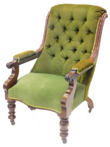 A Victorian mahogany open armchair, with a green buttoned upholstered back, pillared arms and seat, the carved arm rest on shaped supports with turned legs and ceramic castors.