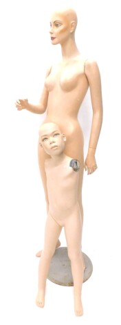 A female mannequin, on metal base and a child mannequin, lacking arms.