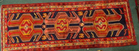 An Azari runner, with three shaped medallions on a blue ground, decorated with animals and birds, 305cm x 110cm.