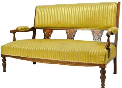 An Edwardian rosewood Sheraton revival salon settee, with overstuffed back, arms and seat, in yellow striped material, with a satinwood inlay, triple pierced splats set with floral patera, shaped arms, turned supports and turned front legs, 89cm H, 128cm