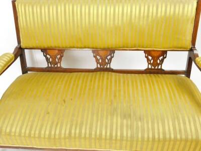 An Edwardian rosewood Sheraton revival salon settee, with overstuffed back, arms and seat, in yellow striped material, with a satinwood inlay, triple pierced splats set with floral patera, shaped arms, turned supports and turned front legs, 89cm H, 128cm - 2