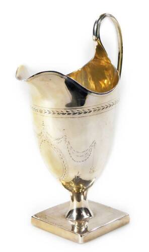 A George III silver helmet shaped cream jug, with strap work handle, raised garlands, an inverted stem and square foot, marks rubbed, 16cm H, 4oz.
