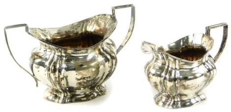 An Edwardian silver milk jug and two handled sugar bowl, 10cm H, each of bombe form on shaped feet with angular handles, Birmingham 1906, 8½oz. (2)